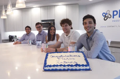 Group of interns smiling with a cake that says, "Congratulations Plexus Interns."